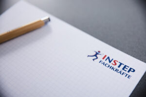 Ein Kugelschreiber liegt auf dem Notizbuch mit dem Logo Instep Fachkräfte auf dem Blatt