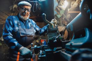 Ein Schlosser in Arbeitskleidung und mit Schutzbrillen bedient im Werkstatt die Maschine